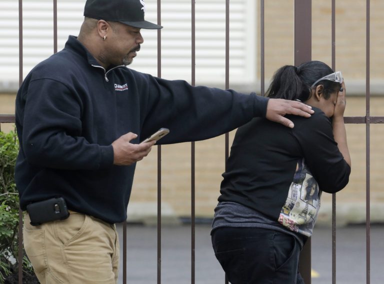 Ge Ge Gatewood, right, reacts after hearing gunshots at the scene where a possible murder suspect has fired shots at officers surrounding a South Side home where he is barricaded Thursday, May 12, 2016, in Chicago. Gateway's two teenage children were in the home next door and went to the basement when they heard the shots. Co-worker Alton Kelly, left, comforts Gatwood at the scene. (AP Photo/M. Spencer Green)