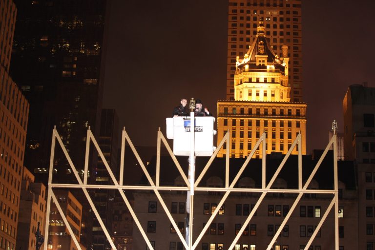   Rabbi Shmuel Butman, Director Lubavitch Youth Organization, right, and Tamir Sapir, head of the Sapir Organization in New York light the 32-foot-tall menorah that weighs about 4,000 pounds and has real oil lamps, protected from the wind by glass chimneys at the edge of Central Park, in New York, Saturday Dec. 8, 2012. (AP Photo/Lubavitch Youth Organization)  