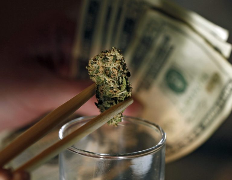 In this Sept. 18, 2012 file photo, a caregiver picks out a marijuana bud for a patient at a marijuana dispensary in Denver.