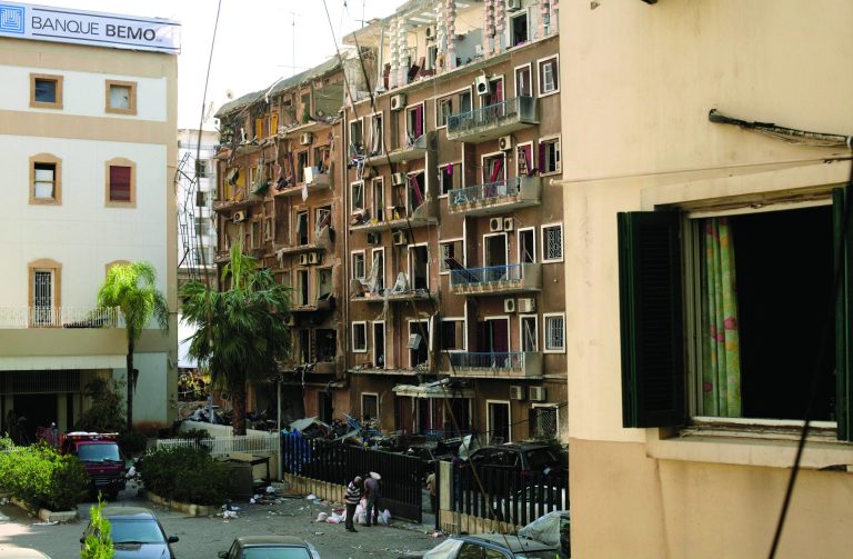 Workers stand near an apartment building severely damaged in a car bomb attack that killed Brig. Gen. Wissam al-Hassan in the Achrafiye district of Beirut, Lebanon, Tuesday, Oct. 23, 2012. Calm returned to the streets of Lebanon's capital on Tuesday, a day after troops launched a major security operation to quell fighting touched off by the assassination of a top anti-Syrian intelligence chief. (AP Photo/Maya Alleruzzo)