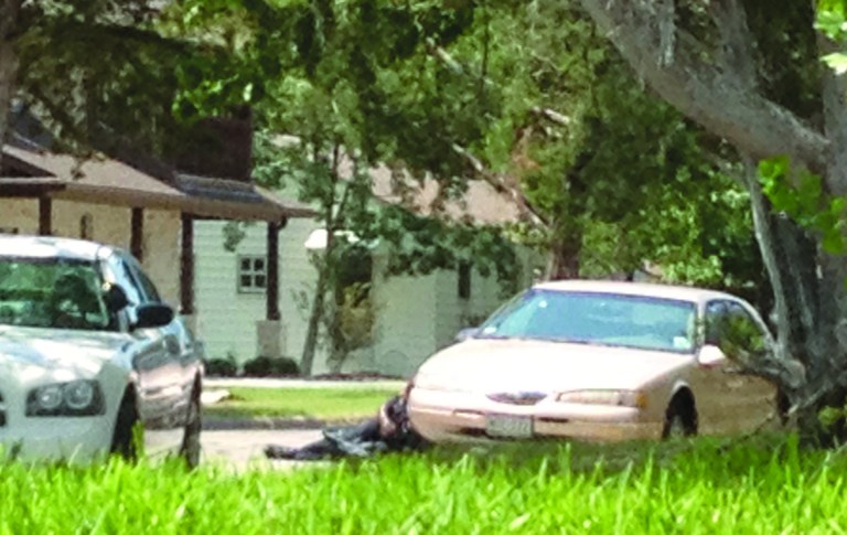 In this Aug. 13, 2012 photo provided by Rigo Cisneros, an officer takes cover, center, behind a vehicle during a shooting at a house in College Station, Texas, near Texas A&M University. Brazos County constable Brian Bachmann, a veteran of 19 years, was making what was supposed to be a routine house call to serve an eviction notice at the property when the recipient, Thomas Alton Caffall, opened fire and shots were exchanged. Bachmann, Caffall and another man were killed by the gunfire. (AP Photo/Rigo Cisneros)