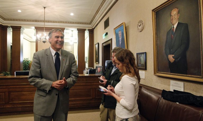 Governor-elect Jay Inslee, left, smiles as he briefly speaks with reporters in the reception area of the office of outgoing Gov. Chris Gregoire Wednesday, Nov. 21, 2012, in Olympia, Wash. At right is a portrait of former Gov. Booth Gardner, 19th governor of Washington. Inslee was meeting with Gregoire to discuss his transition to the position. He will be sworn in as governor in January of 2013. (AP Photo/Elaine Thompson)