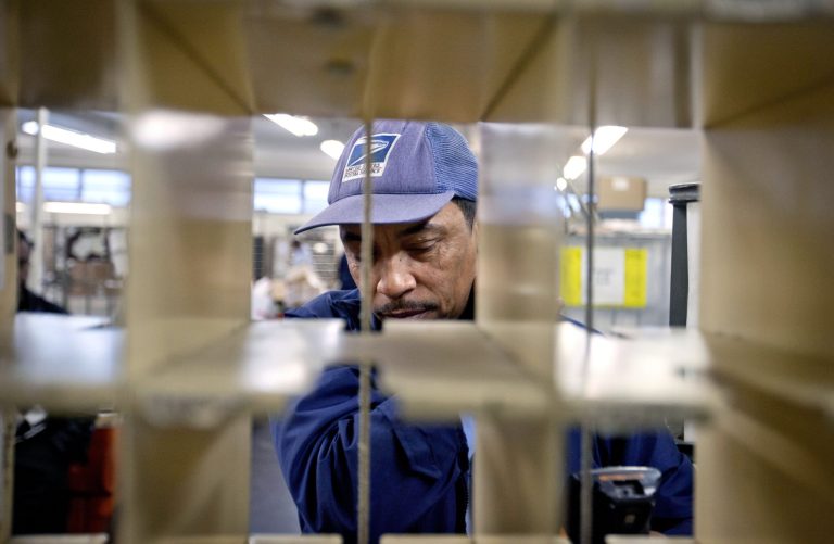   FILE - In this Thursday, Feb. 7, 2013, file photo, U.S. Postal Service letter carrier of 19 years, Michael McDonald, gathers his belongings in the East Atlanta post office before making his delivery run, in Atlanta. The Postal Service said Friday, Aug. 9, 2013, that it trimmed its losses to $740 million over the last three months by consolidating processing facilities, cutting hours for workers and post offices and reducing workers' compensation costs. (AP Photo/David Goldman, File)  