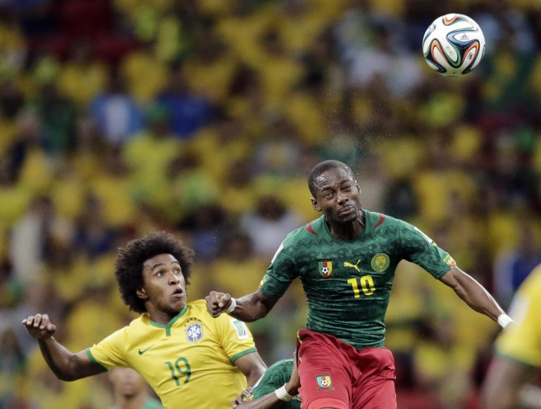 Brazil's Willian watches as Cameroon's Vincent Aboubakar heads the ball during the group A World Cup soccer match between Cameroon and Brazil at the Estadio Nacional in Brasilia, Brazil, Monday, June 23, 2014. (AP Photo/Bernat Armangue)