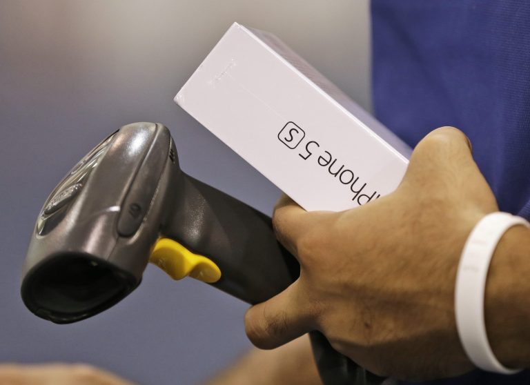FILE - In this  Friday, Sept. 20, 2013, file photo, a Best Buy employee prepares to scan a new iPhone 5S during the opening day of sales of the new phone in Richmond, Va. (AP Photo/Steve Helber, File)