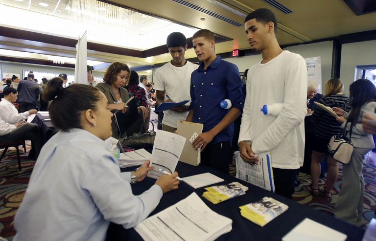 FILE - In this Wednesday, Aug., 14, 2013, file photo, job seekers Emilio Ferrer, Brian Ferrer,  center, and Jonathan, right, of  Hollywood, Fla., talk to a FirstService representative at a job fair in Miami Lakes, Fla. The Labor Department reports on the number of Americans who applied for unemployment benefits for the last week of October on Thurday, Oct. 31, 2013. (AP Photo/Alan Diaz, File)