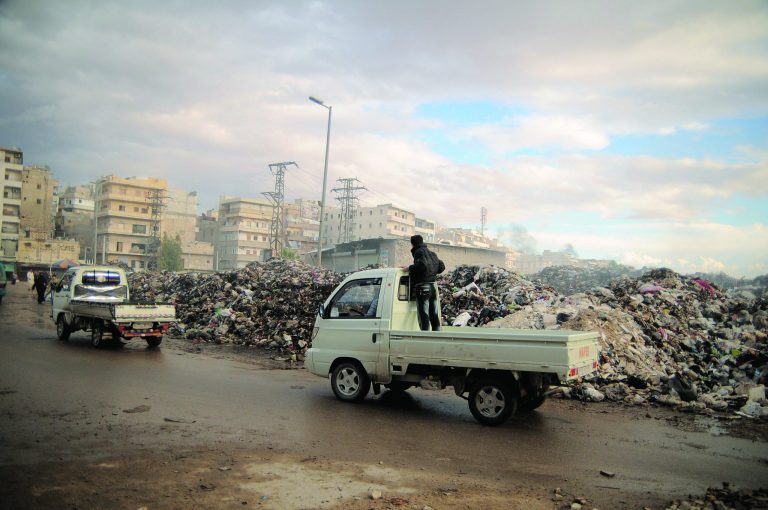 In this Saturday, Nov. 10, 2012 photo, trucks pass a mountain of garbage in a roundabout in Aleppo, Syria. Due the heavy fighting and shelling, the garbage collection system collapsed weeks ago. (AP Photo/M?nica G. Prieto)