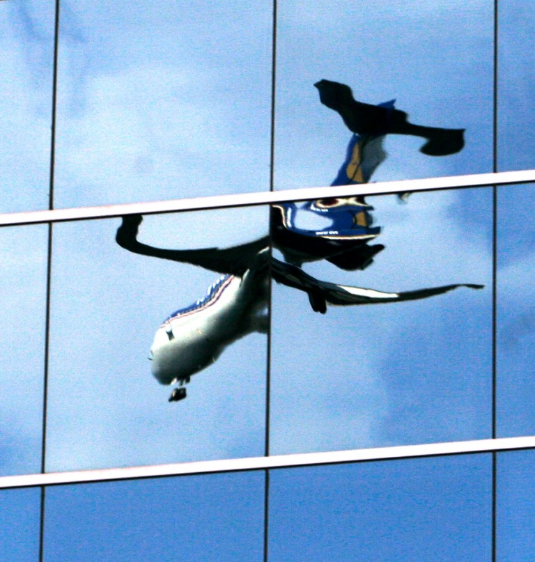 CORRECTS LOCATION OF AIRPORT - FILE - In this Sept. 3, 2007, file photo, a twisted reflection of a passenger jet is reflected in the mirrored windows of an office building as it lands at Washington's Reagan National Airport in Arlington, Va. The government wants to dramatically reduce the height limits of buildings near hundreds of airports, but the proposal is drawing fire from real estate developers, local business leaders and members of Congress who say it will reduce property values. (AP Photo/J. David Ake, File)