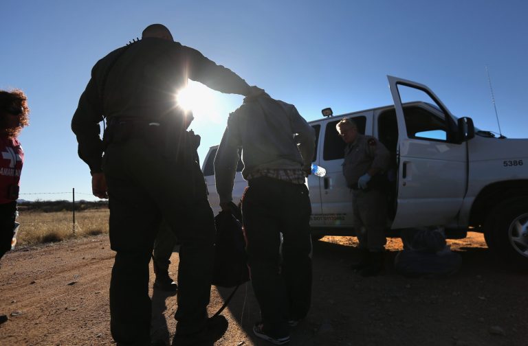WALKER CANYON, AZ - MARCH 06:  A U.S. Border Patrol agent takes an immigrant into custody after his group of eight Mexicans was caught while crossing illegally into the United States on March 6, 2013 near Walker Canyon, Arizona. Due to broad federal sequestration budget cuts, Border Patrol agents are expected to begin taking unpaid furlough days in April, as Customs and Border Protection funding is expected to be reduced by more than $500 million.  (Photo by John Moore/Getty Images)