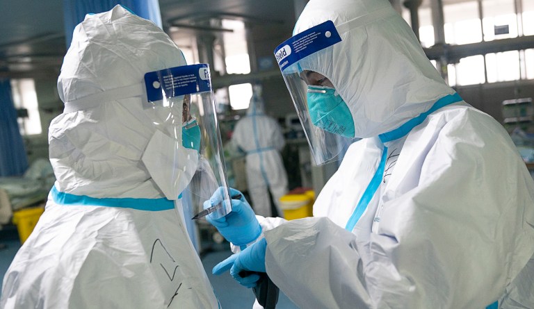 A woman wears a mask as an employee works to prevent a new coronavirus at Suseo Station in Seoul, South Korea, Friday, Jan. 24, 2020. China broadened its unprecedented, open-ended lockdowns to encompass around 25 million people Friday to try to contain a deadly new virus that has sickened hundreds, though the measures' potential for success is uncertain.