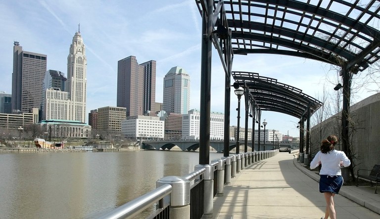 FILE - In this March 15, 2004, file photo, a woman runs the Franklinton floodwall next to the Scioto River in Columbus, Ohio. The largest city named for Christopher Columbus has called off its observance of the holiday named for the explorer. Offices in Columbus, Ohio, will remain open Monday, Oct. 8, 2018, and close on Veterans Day instead.