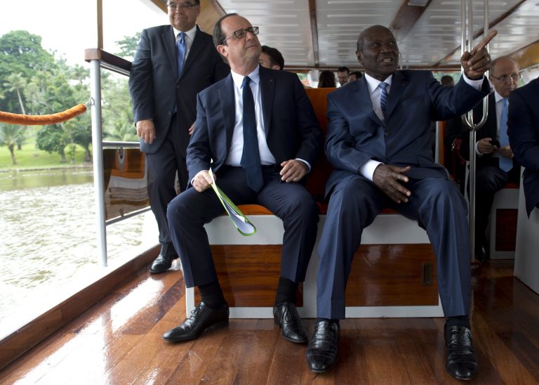 French President Francois Hollande, left, sits next to Ivorian Prime Minister Daniel Kablan Duncan, right, on a boat, Thursday, July 17, 2014 on Abidjan's lagoon, Ivory Coast, where French construction company Bouygues is building a third bridge that is presented as a key project by the Ivorian government. Hollande starts a 3-day visit to Ivory Coast, Niger and Chad. (AP Photo/Alain Jocard, Pool)