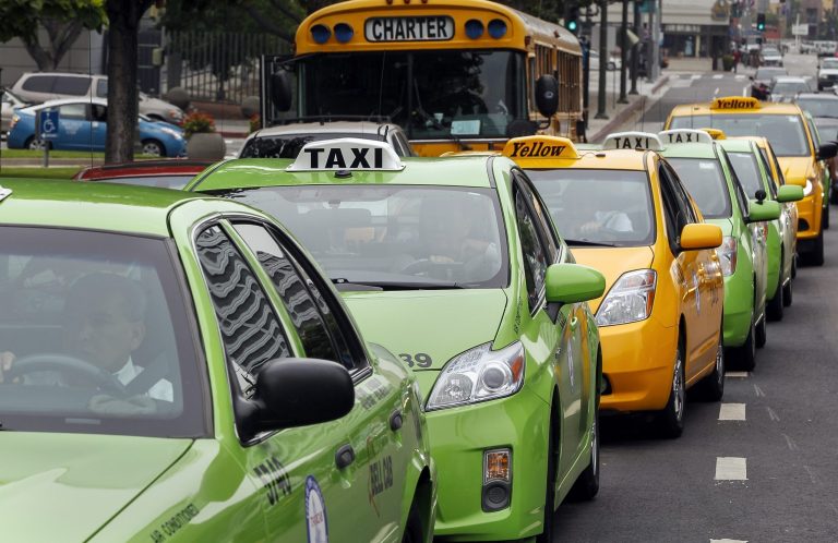 Los Angeles-area taxi drivers circle City Hall in their cabs in protest of unregulated ride-share services being promoted through smartphone applications and social media in Los Angeles in June 2013. (AP Photo/Damian Dovarganes)