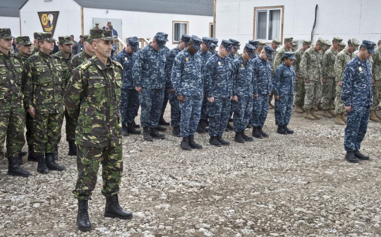 In this handout photograph from the US Navy, US service members deployed to the Naval Support Facility (NSF) Deveselu, groups center and right, bow their heads with members of the Romanian Military, left, during a religious moment of the establishment and assumption of command ceremony in Deveselu, Romania, Friday, Oct. 10, 2014. The NSF Deveselu Base, established more than 20 years ago, will be part of the Aegis Ballistic Missile Defense (BMD) System. The US Navy has taken control of a new missile defense base in southern Romania, one of two European land-based interceptor sites for a NATO missile shield which Russia strongly opposes.(AP Photo/U.S. Navy / LT j.g. Alexander Perrien, Handout)
