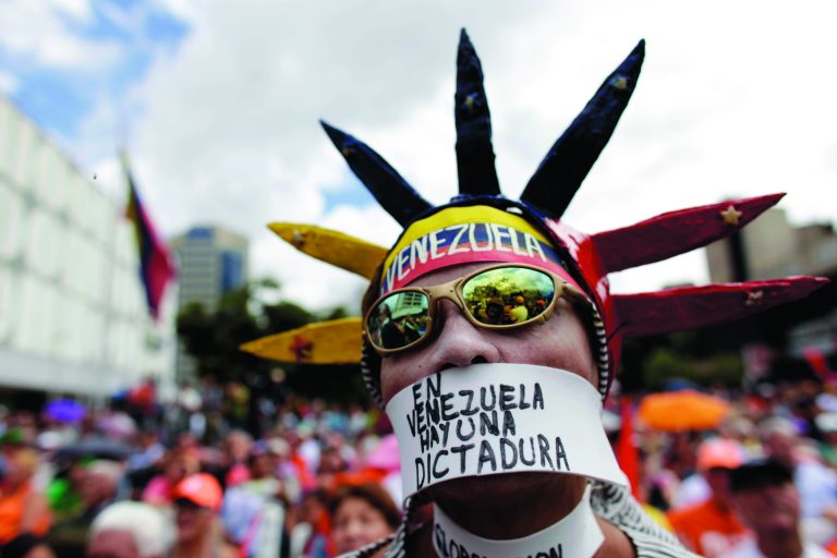 An opponent of Venezuela's President Hugo Chavez wears a message over his mouth that reads in Spanish; 