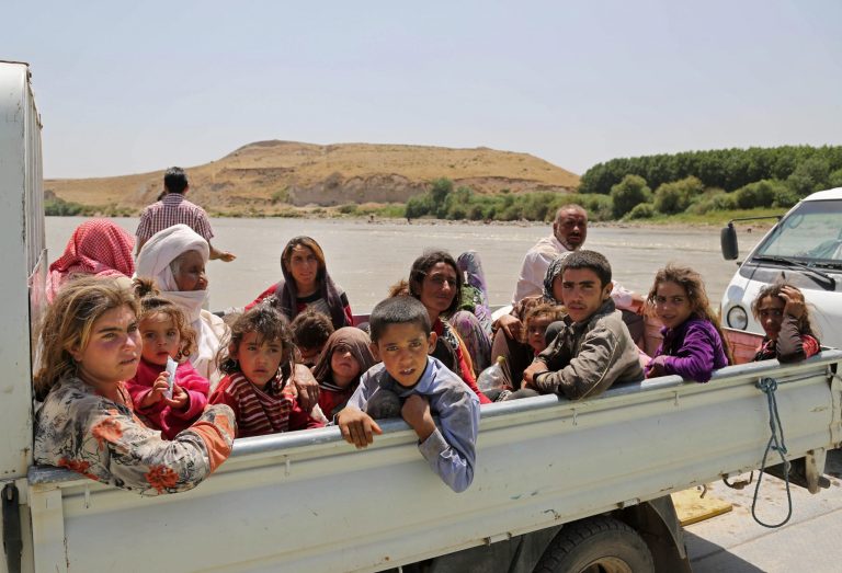 In this Sunday, Aug. 10, 2014, displaced Iraqis from the Yazidi community cross the Iraq-Syria border at Feeshkhabour bridge over Tigris River at Feeshkhabour border point, northern Iraq. Kurdish authorities at the border believe some 45,000 Yazidis passed the river crossing in the past week and thousands more are still stranded in the mountains. (AP Photo/Khalid Mohammed)