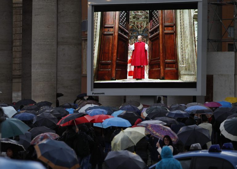 People watch on a video monitor in St. Peter's Square as Monsignor Guido Marini, master of liturgical ceremonies, closes the double doors to the Sistine Chapel in Vatican City Tuesday, March 12, 2013, at the start of the conclave of cardinals to elect the next pope. Marini closed the doors after shouting 