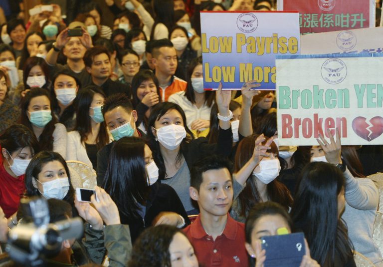   In this Dec. 10, 2012 photo, members of the Cathay Pacific Airways Flight Attendants Union participate in a rally before voting for industrial action after negotiations with the airline broke down. Flight attendants at Hong Kong airline Cathay Pacific Airways are threatening to withhold food, alcohol and even smiles from passengers during the Christmas holidays over a pay dispute, a union official said Thursday. Cabin staff at the airline, which has a reputation for top-notch service, voted at the union meeting this week in favor of industrial action that could also result in flight delays. (AP Photo/Str)  
