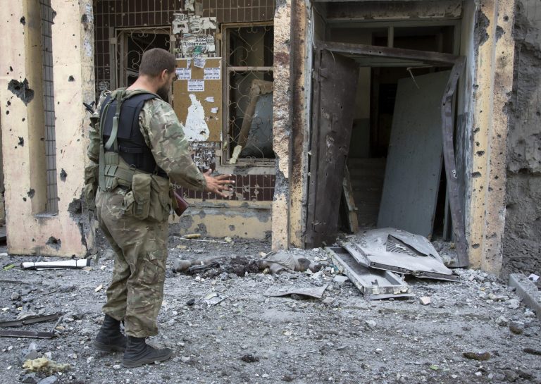 A pro-Russian fighter gestures near a body of a community service worker who was killed during the shelling outside a residential apartment house in Donetsk, eastern Ukraine Tuesday, July 29, 2014.  Local residents said it was a shelling from direction of Ukrainian army's positions. (AP Photo/Dmitry Lovetsky)