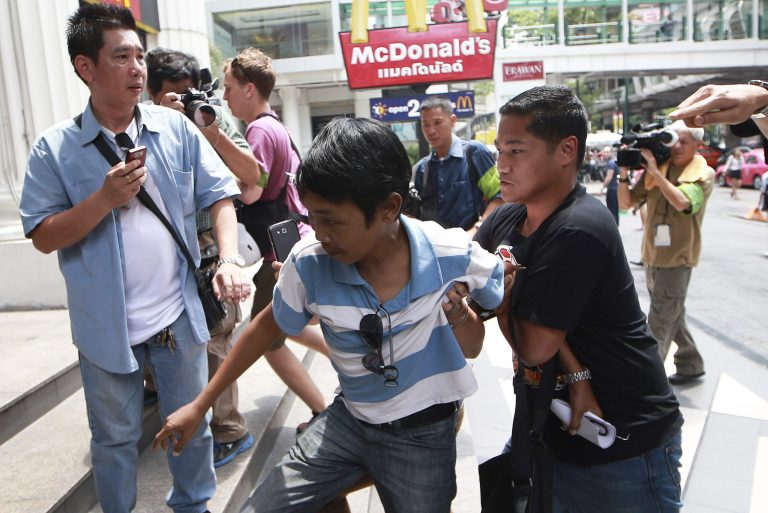 A man, center, is detained by plainclothes police officers after holding an anti-coup sign outside a McDonald's restaurant in downtown Bangkok, Thailand Saturday, May 31, 2014. In his first address to the public since taking control of Thailand in a bloodless coup, army commander Gen. Prayuth Chan-ocha, the head of the military junta, said it could take more than a year for new elections to be held because peace and reforms must be achieved first. (AP Photo/Wason Wanichakorn)