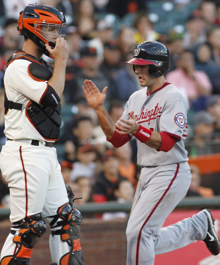 Washington Nationals' Steve Lombardozzi claps his hands as he scores in front of San Francisco Giants' Buster Posey during the first inning of a baseball game, Monday, Aug. 13, 2012 in San Francisco, Calif.  (AP Photo/George Nikitin)