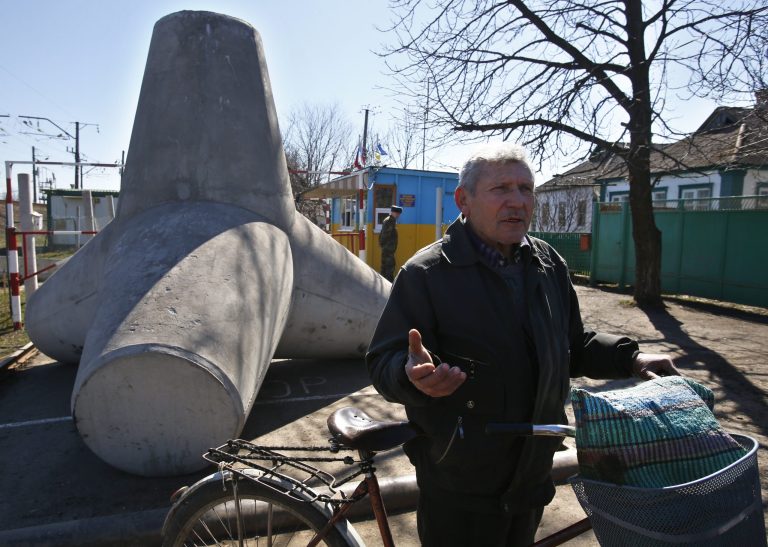 In this photo taken Monday, March 24, 2014, Russian citizen, retired doctor  Nikolai Chernyshev speaks after crossing crossing a Ukrainian-Russian border in the village of Vyselki, eastern Ukraine. Ever since the 1991 breakup of the Soviet Union, the village of Vyselki has been split between Ukraine and Russia. For years its residents have continued to live together peacefully, doing most of their shopping in one country and paying their electricity bills in another. But after Russia seized the Crimean Peninsula from Ukraine, the Ukrainian villagers fear a further incursion of Russian troops, while the Russians say they would welcome their protection against the new pro-Western government in Kiev. (AP Photo/Sergei Grits)