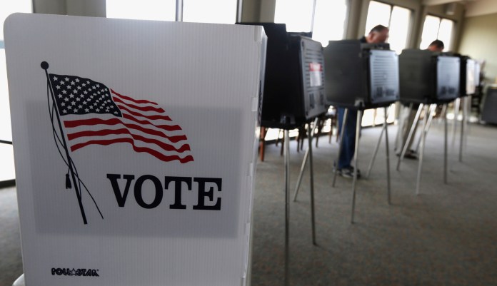 FILE - In this March 18, 2014 file photo, voters cast their ballots in Hinsdale, Ill. Illinois election officials voted Monday, MOV. 20, 2017, to remain in a controversial multi-state voter registration database, but critics who raised questions about inaccuracies and security vowed to take the fight to the state Legislature.For weeks, advocates and top Illinois Democrats, including both U.S. senators, have urged election officials to withdraw from the Kansas-run Interstate Voter Registration Crosscheck Program.