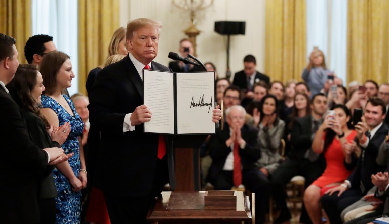 President Donald Trump holds up an executive order on "improving free inquiry, transparency, and accountability on campus" after signing in the East Room of the White House, Thursday, March 21, 2019, in Washington.