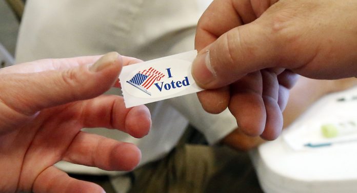 A poll worker at this Ridgeland, Miss., precinct hands out "I Voted" stickers to all who exit the voting booths, Tuesday, Aug. 4, 2015. (AP Photo)Â 