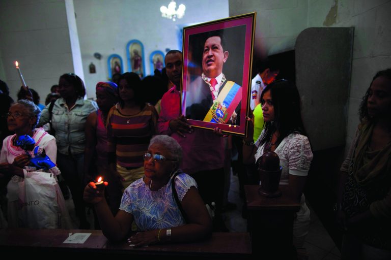 Venezuelan embassy workers hold up a framed image of Venezuela's ailing President Hugo Chavez during the monthly Catholic service devoted to the sick at the Church of Our Lady of Regla, in Regla, across the bay from Havana, Cuba, Tuesday, Jan. 8, 2013. Venezuela's government said Monday, Chavez is in a 