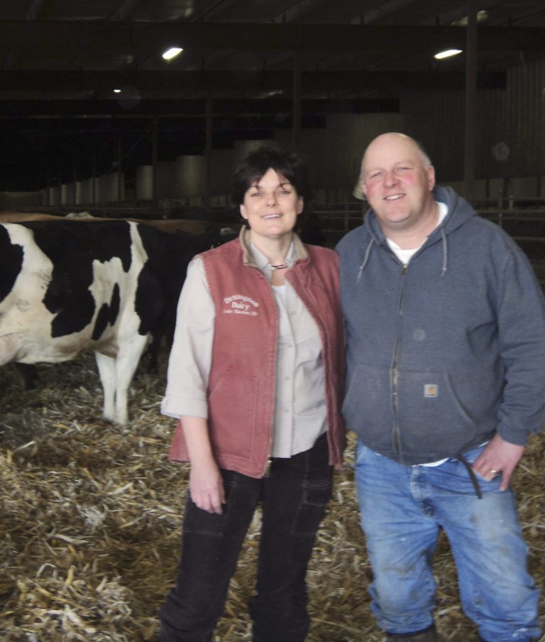 This March 2012 photo provided by Rodney and Dorothy Elliott show the couple inside inside the barn at their Drumgoon Dairy near Lake Norden, S.D. The couple, who moved their dairy from Ireland to South Dakota, says the EB-5 visa program helped them start with a larger barn. Dorothy Elliott says it was funded in part by four foreign investors who put up $500,000 each and in exchange, they are now U.S. citizens. (AP Photo/Courtesy of Rodney and Dorothy Elliott)
