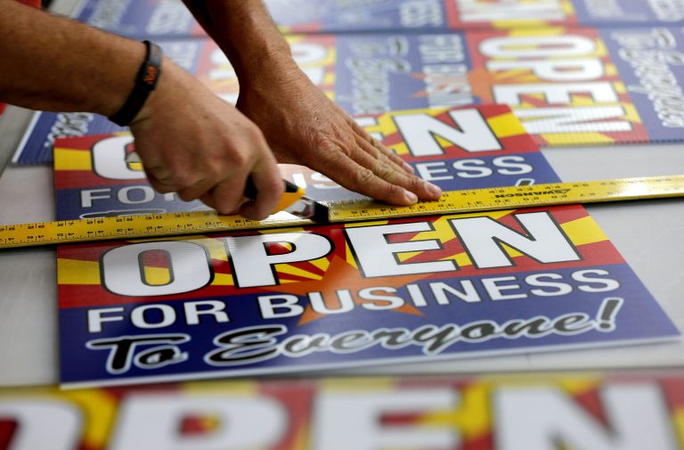 Tom Cushing, a production expert at Fast Signs, cuts down a sheet of anti-Senate Bill 1062 signs that read 