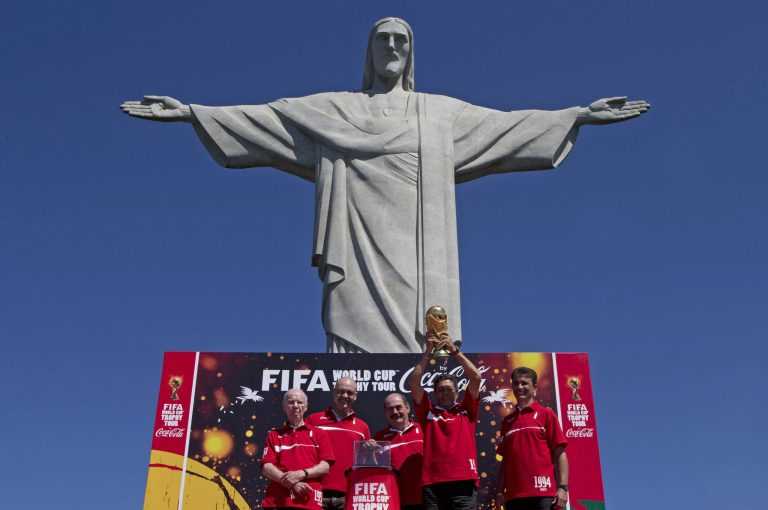 FILE - In this Thursday, Sept. 12, 2013 file photo, Brazil's former World Cup champions, from left, Zagallo, Marcos, Rivellino, Amarildo who holds the World Cup, and Bebeto pose for a photo below the Christ the Redeemer statue at the launch of the FIFA World Cup Trophy Tour in Rio de Janeiro, Brazil. World Cup sponsor Coca-Cola has disclosed contingency plans to soften the celebratory tone of its sponsorship of football's showpiece event in Brazil if unrest returns to the streets. (AP Photo/Silvia Izquierdo, File)