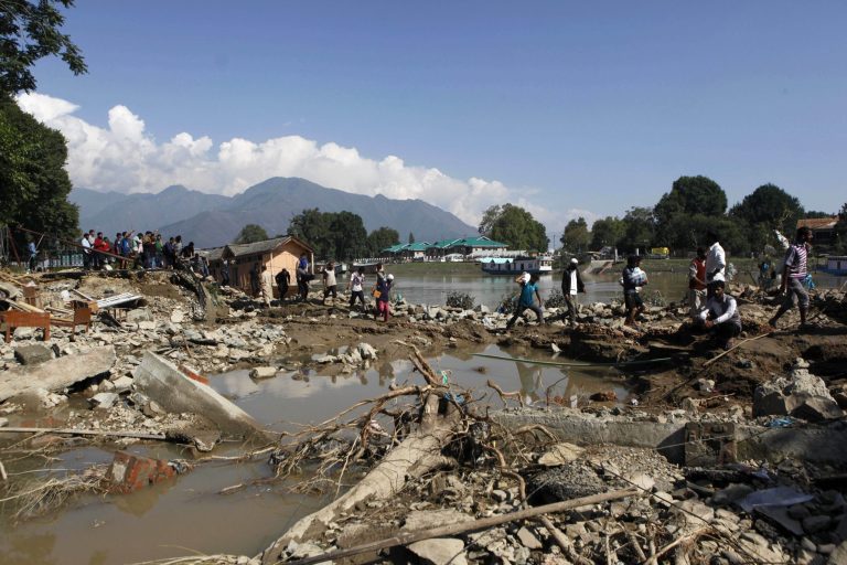 Kashmiri walk past a breached river bank of the River Jhelum in Srinagar, India, Saturday, Sept. 13, 2014. About 200 people have died in Indian-controlled Kashmir, where floodwaters have receded, enabling people to return to their homes. Medical teams in Srinagar, the main city in Indian-held Kashmir, were stepping up efforts to prevent the spread of waterborne diseases, officials said Saturday. (AP Photo/Dar Yasin)