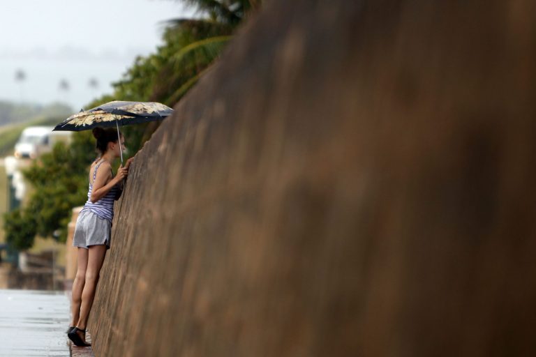 A woman looks over the seaside wall of the 16th century Spanish fort El Morro, under cloudy skies in San Juan, Puerto Rico, Saturday, Aug. 2, 2014. Bertha pushed just south of Puerto Rico on Saturday as it unleashed heavy rains and strong winds across the region. (AP Photo/Ricardo Arduengo)