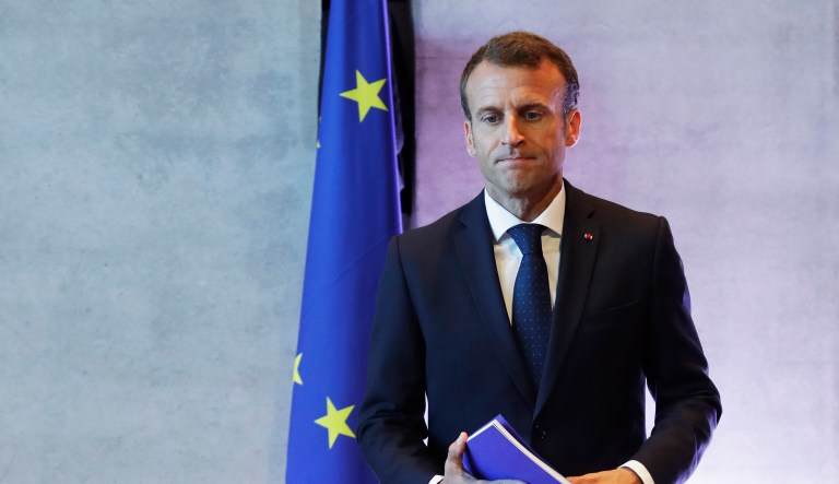 French President Emmanuel Macron holds a book at the beginning of the plenary session of the informal EU summit in Salzburg, Austria, Thursday, Sept. 20, 2018.