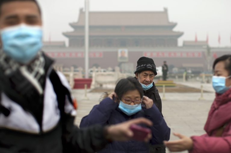 Tourists put on their masks after they posed for souvenir photos as they visit Tiananmen Square on a severely polluted day in Beijing, China, Tuesday, Feb. 25, 2014.  Pollution across a large swath of northern China worsened on Tuesday. (AP Photo/Alexander F. Yuan)