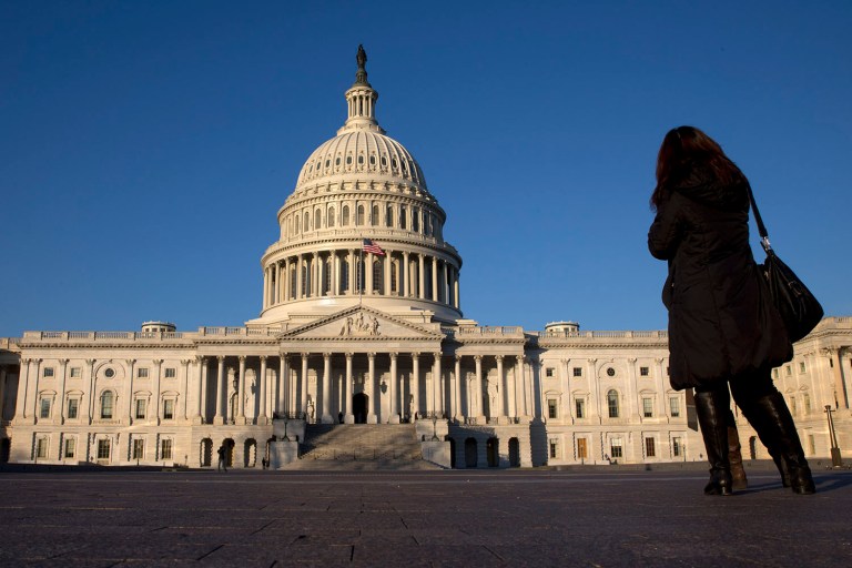 FILE - In this Dec. 31, 2013, file photo, a woman looks at the U.S. Capitol in Washington. After last fall's tumultuous, bitterly partisan debt ceiling and government shutdown battles, a sense of fiscal fatigue seems to be setting in among many Washington policymakers as President Barack Obama prepares for his fifth State of the Union address later this month. (AP Photo/Jacquelyn Martin, File)