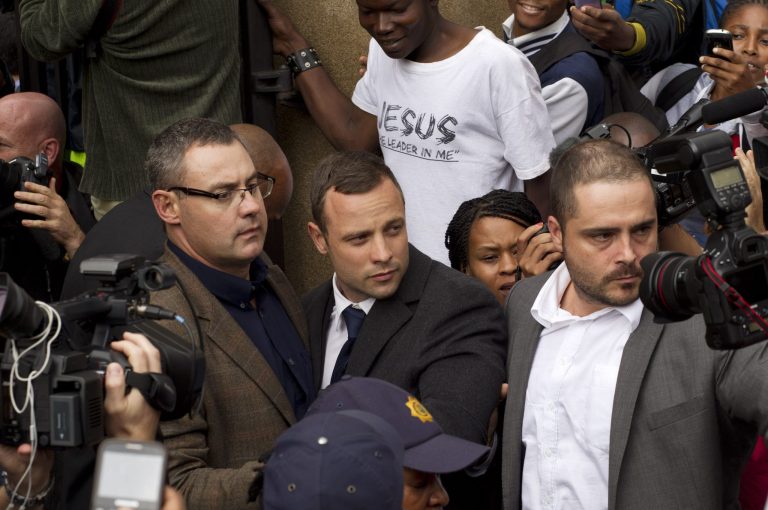 Oscar Pistorius, center, is escorted out by police officers as he leaves  the high court on the second day of his trial in Pretoria, South Africa, Monday, March 3, 2014. Oscar Pistorius is charged with murder for the shooting death of his girlfriend, Reeva Steenkamp, on Valentines Day in 2013. (AP Photo/Themba Hadebe)