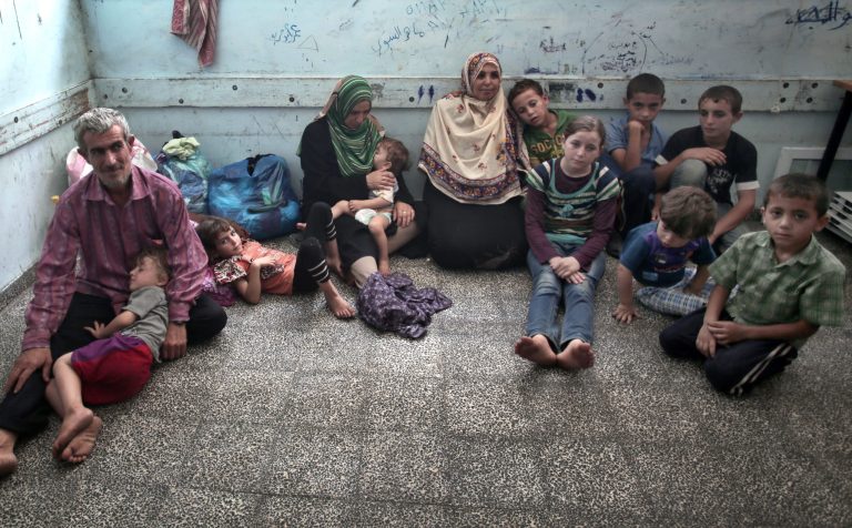 In this Monday, July 14, 2014 photo, sisters Mariam Attar, center right, and Sada Attar, center left, rest with their children inside the New Gaza Boys United Nations School after fleeing their home in fear of Israeli airstrikes in Gaza City. The children of the Attar clan have lived through three wars in just over five years, each time fleeing their homes as Israel bombarded their neighborhood in the Palestinian Gaza Strip. (AP Photo/Khalil Hamra)