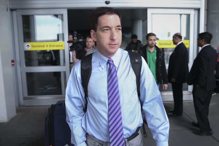 Journalist Glenn Greenwald steps out of Terminal 4 after arriving at John F. Kennedy International Airport Friday, April 11, 2014, in New York. Greenwald and Laura Poitras of the Guardian share a George Polk Award for national security reporting with The Guardian's Ewen MacAskill and Barton Gellman, who has led The Washington Post's reporting on the NSA documents.  (AP Photo/John Minchillo)