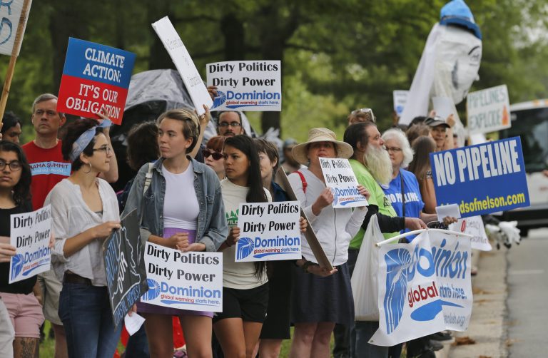 Protesters carry signs along the roadway leading to Dominion Virginia Power's annual meeting in Richmond, Va. Protesters are trying to block the construction of a natural gas pipeline through rural Virginia. (AP Photo/Steve Helber)