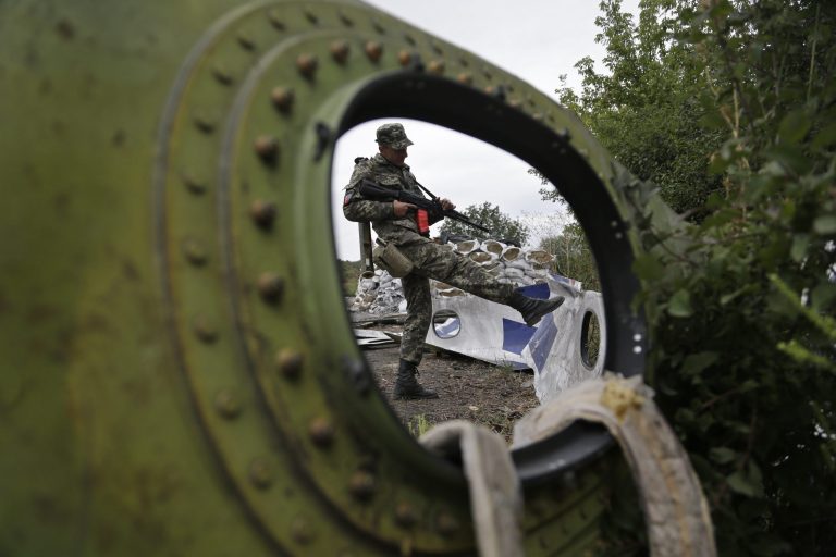 A Pro-Russian rebel looks at pieces of the Malaysia Airlines Flight 17 plane near village of Rozsypne, eastern Ukraine, Tuesday, Sept. 9, 2014. The Dutch team investigating the downing of Malaysia Airlines Flight 17 over Eastern Ukraine says the crash was likely caused by the plane being hit by multiple 