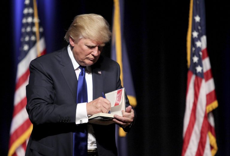 Republican presidential candidate businessman Donald Trump signs a copy of his book 