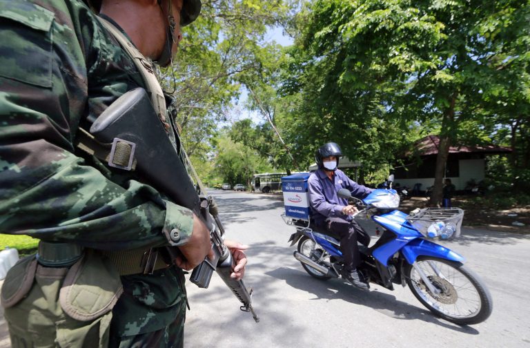 A Thai soldier looks at a motorcyclist riding past while providing security near the pro-government demonstration site on the outskirts of Bangkok, Thailand Wednesday, May 21, 2014. Thailand began its second day under martial law Wednesday with little visible military presence on the streets of Bangkok as residents tried to make sense of the dramatic turn of events after six months of anti-government protests and political turmoil. (AP Photo/Wason Wanichakorn)