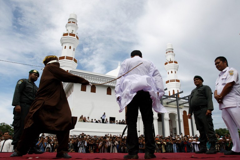 An Islamic Shariah law official whips a man convicted of gambling. (AP Photo/Heri Juanda)