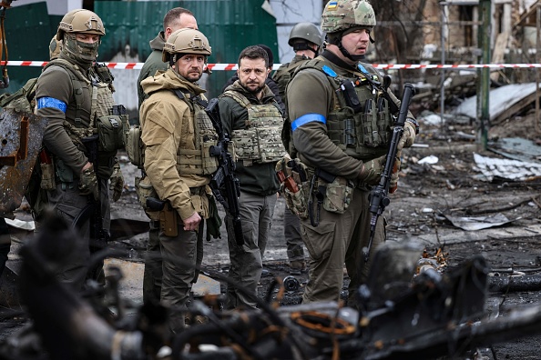 Ukrainian President Volodymyr Zelensky (center) walks in the town of Bucha, northwest of the Ukrainian capital Kyiv, on Monday. Zelensky said Sunday that the Russian leadership was responsible for the civilian killings in Bucha, where bodies were found lying in the street after the town was retaken by the Ukrainian army.