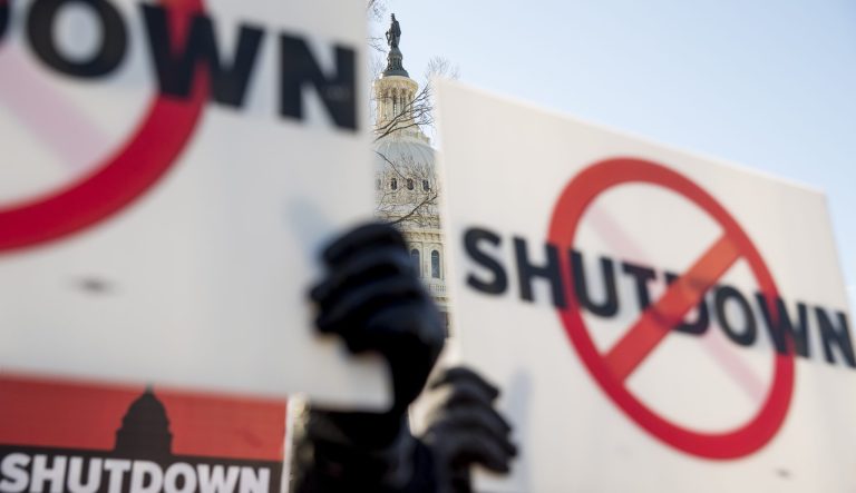 The Capitol is visible behind signs protesting a government shutdown.