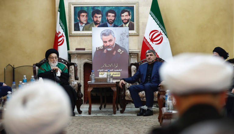 Fighters with Iran-backed militias in Iraq known as the Popular Mobilization Forces, wave Iraqi flags while mourners and family members prepare to bury the body of Abu Mahdi al-Muhandis, deputy commander of Iran-backed militias who was killed in a US airstrike in Iraq on Friday, in Wadi al-Salam, or "Valley of Peace" cemetery, during his funeral procession in Najaf, Iraq, Wednesday, Jan. 8, 2020. 