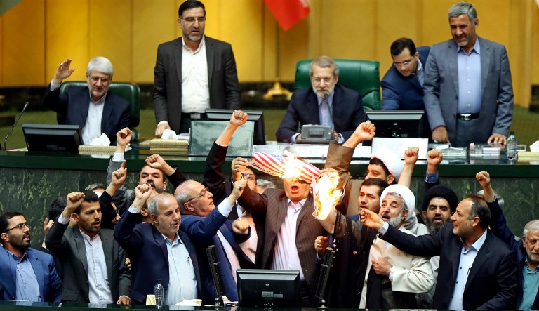 Iranian lawmakers burn two pieces of papers representing the U.S. flag and the nuclear deal as they chant slogans against the U.S. at the parliament in Tehran.